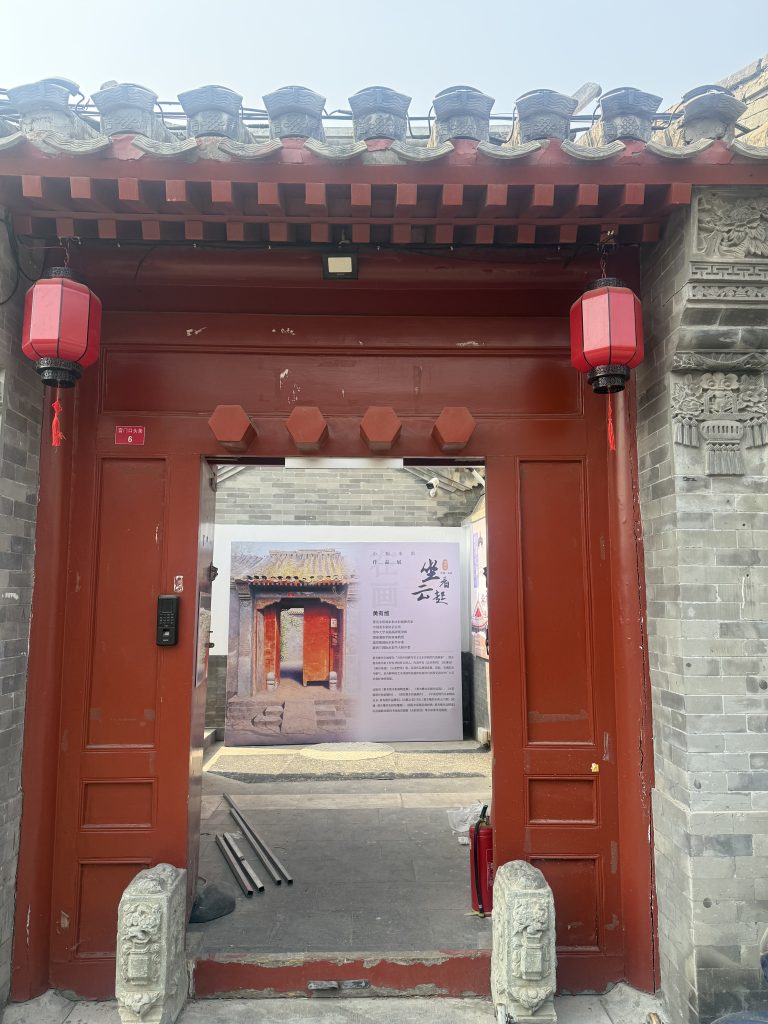 Exterior view of the historic traditional Chinese courtyard with red doors and grey brick walls serving as the venue for the watercolor exhibition in Beijing.