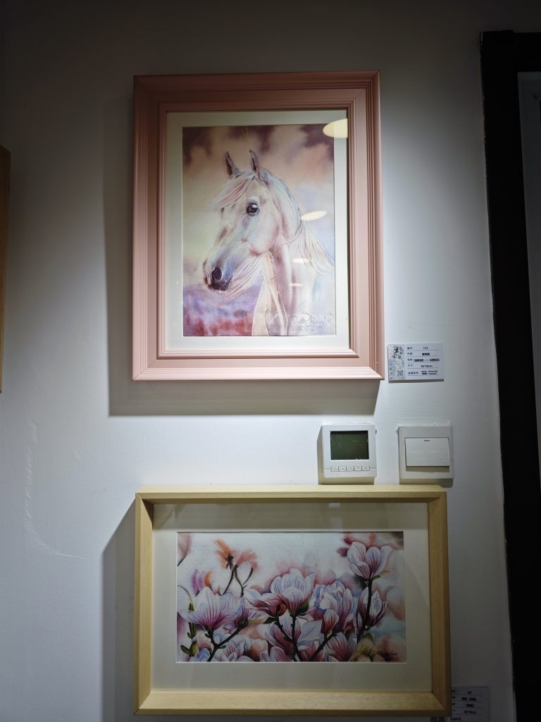 Yanqing Huang's watercolor painting "Luminous Dawn Horse" professionally framed in pink and displayed on the white wall of the Beijing courtyard gallery.